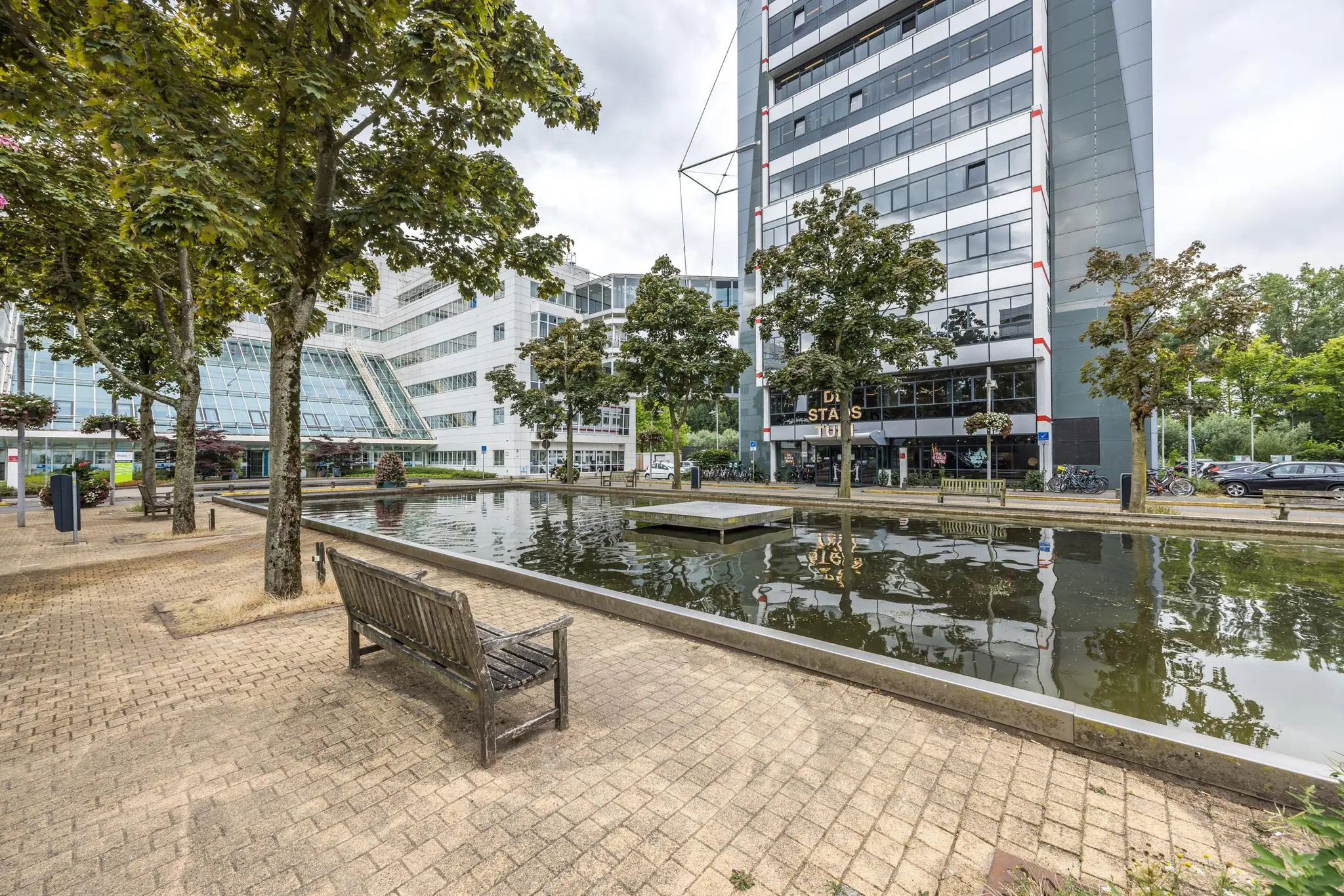 Moderne kantoorgebouwen aan de Daltonlaan in Utrecht met een vijver en zitbanken op de voorgrond.