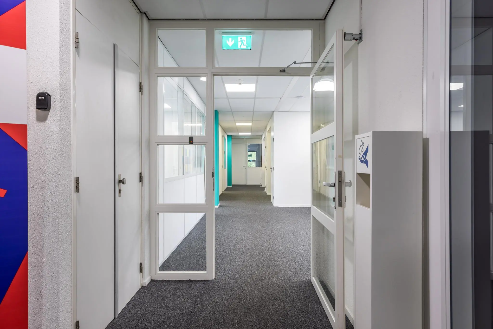 Verlicht kantoorinterieur aan de Daltonlaan met open deur en zicht op lange gang.