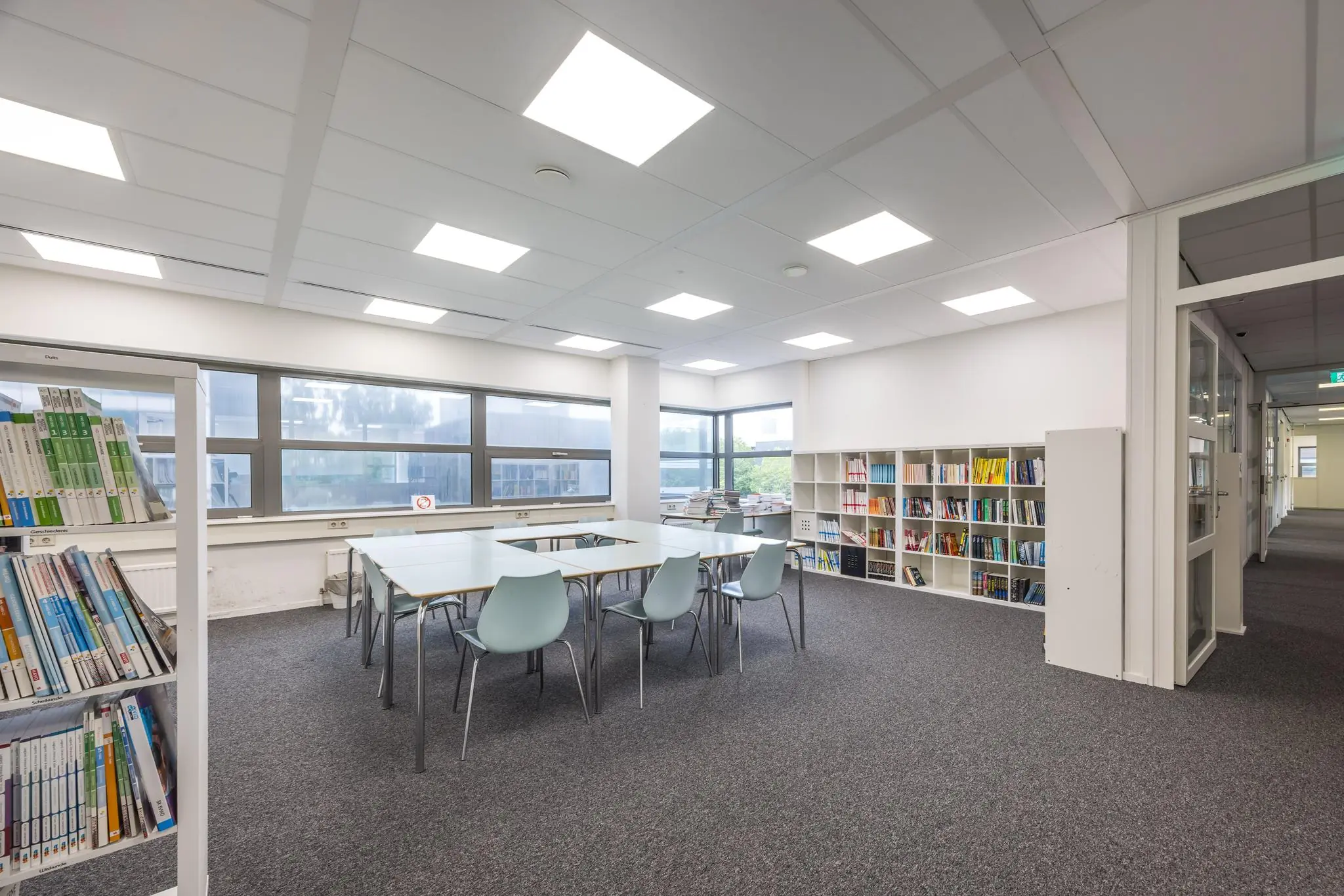 Moderne lees- en studieruimte aan de Daltonlaan met boekenplanken, bureaus en stoelen.