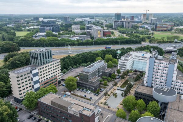 Luchtfoto van het kantoorgebied aan de Daltonlaan in Utrecht met diverse moderne gebouwen, vijvers en een snelweg op de achtergrond.