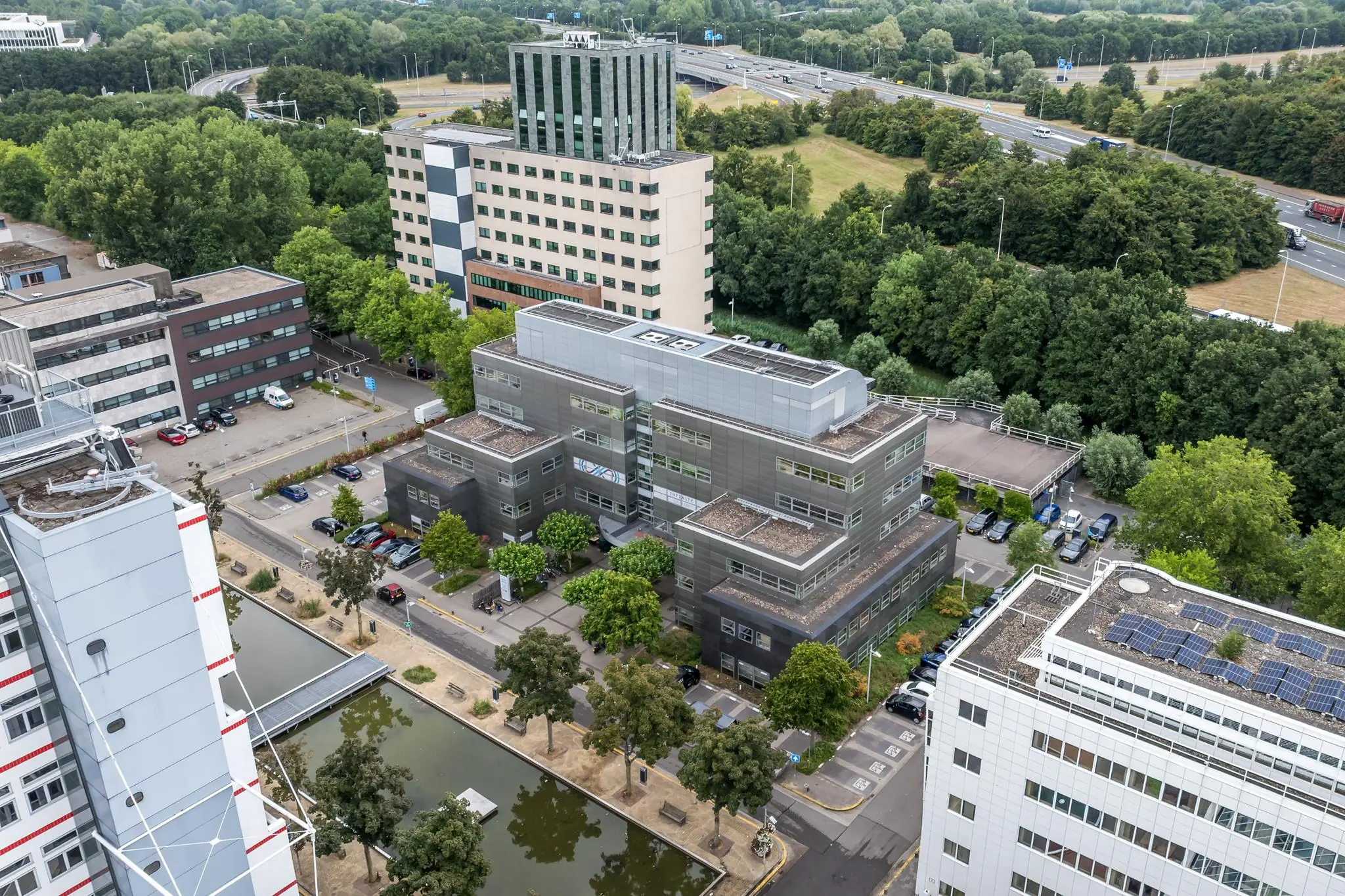 Luchtfoto van kantoorpanden aan de Daltonlaan in Utrecht, omringd door groen en nabij een snelweg.