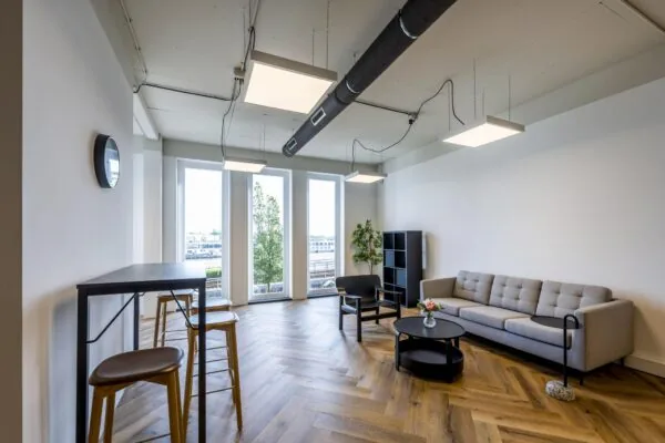 Modern ingerichte lounge- en werkruimte aan de De Ruijterkade met grote ramen, houten visgraatvloer en minimalistisch meubilair.