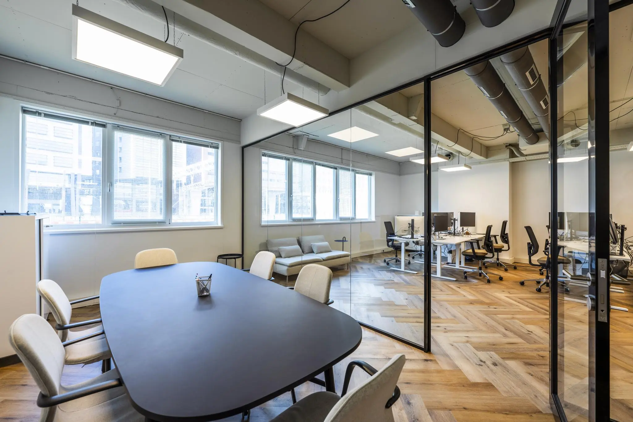 Moderne kantoorruimte aan de De Ruijterkade met een vergadertafel, glazen wand en uitzicht op werkplekken.