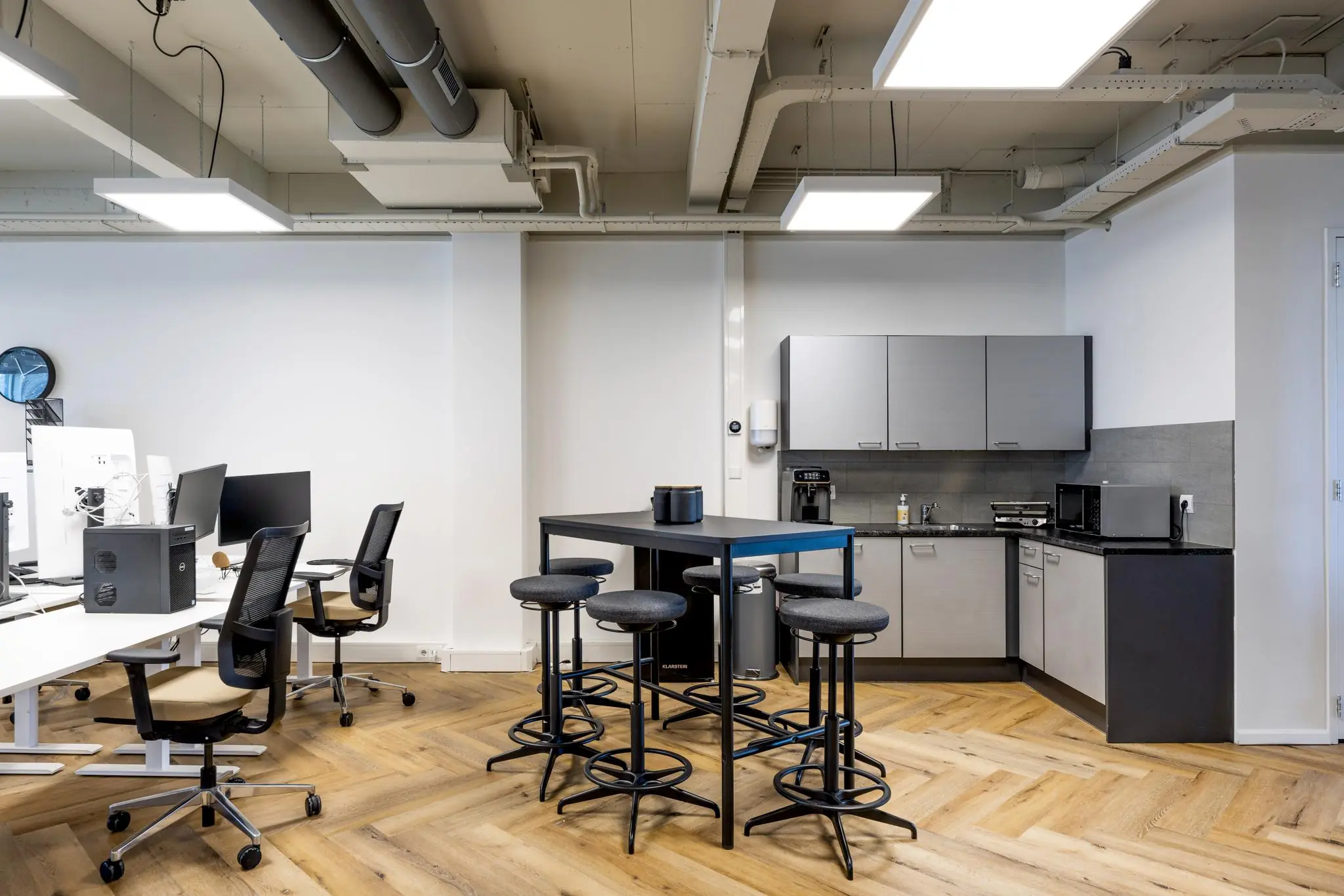 Moderne kantoorruimte aan de De Ruijterkade met werkplekken, een kitchenette en een hoge tafel met barkrukken.