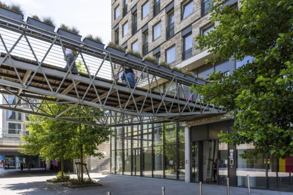 Een moderne voetgangersbrug met plantenbakken verbindt twee gebouwen bij het Elizabeth Cady Stantonplein.