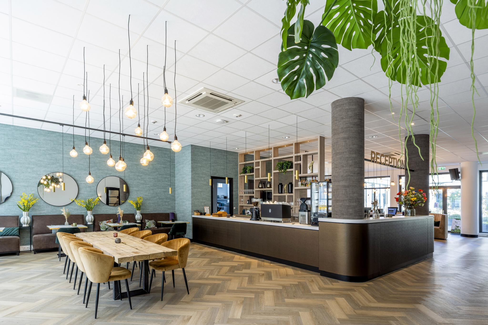 Moderne en stijlvol ingerichte ontvangsthal met houten vloer, zithoek, hanglampen en een receptiebalie aan het Elizabeth Cady Stantonplein.