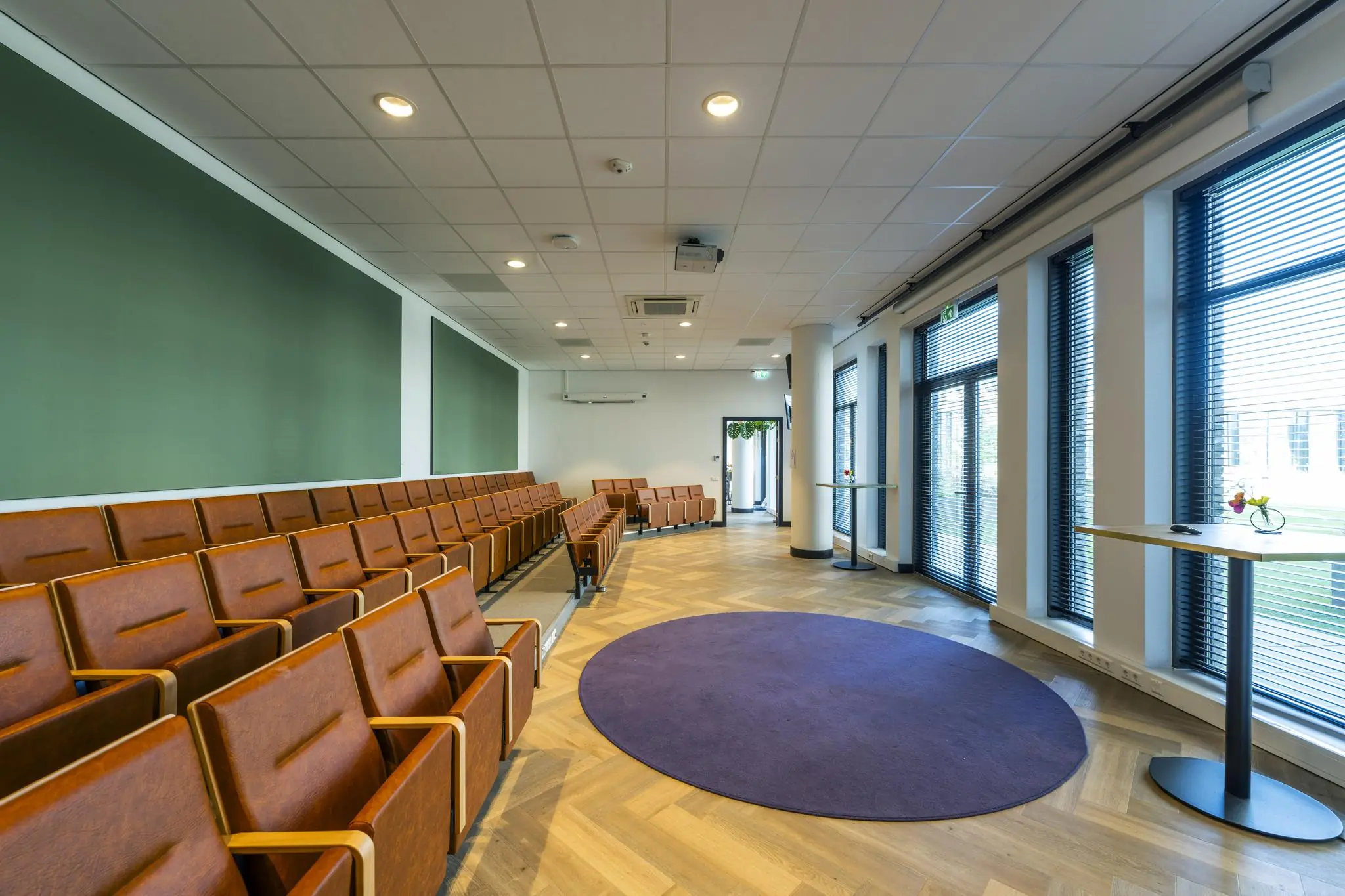 Moderne vergaderruimte op het Elizabeth Cady Stantonplein met leren stoelen, houten vloer en grote ramen met jaloezieën.