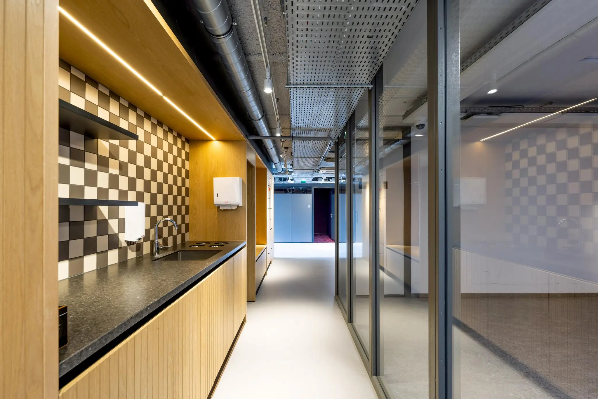 Moderne kantoorkeuken met zwart-wit geblokte tegelwand en houten afwerking aan het Elizabeth Cady Stantonplein.