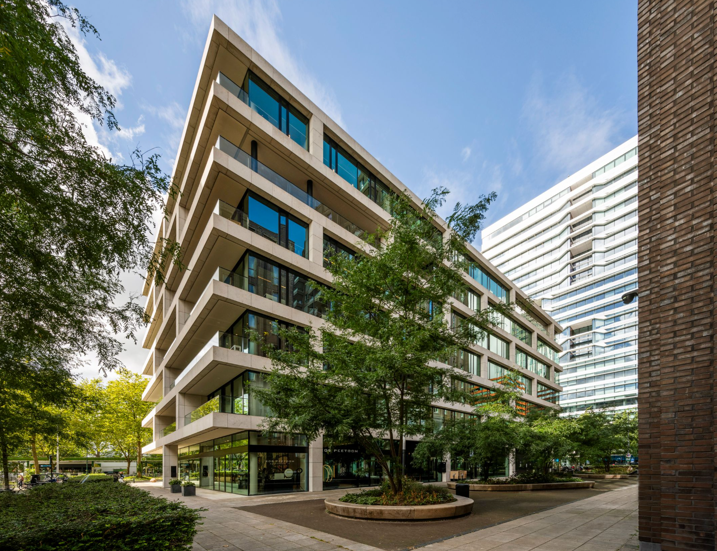 Modern kantoorgebouw aan de Gustav Mahlerlaan in Amsterdam met grote ramen en omringd door bomen.