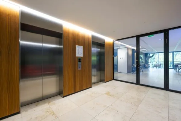 Moderne liftlobby met houten afwerking en glazen deur aan de Gustav Mahlerlaan.