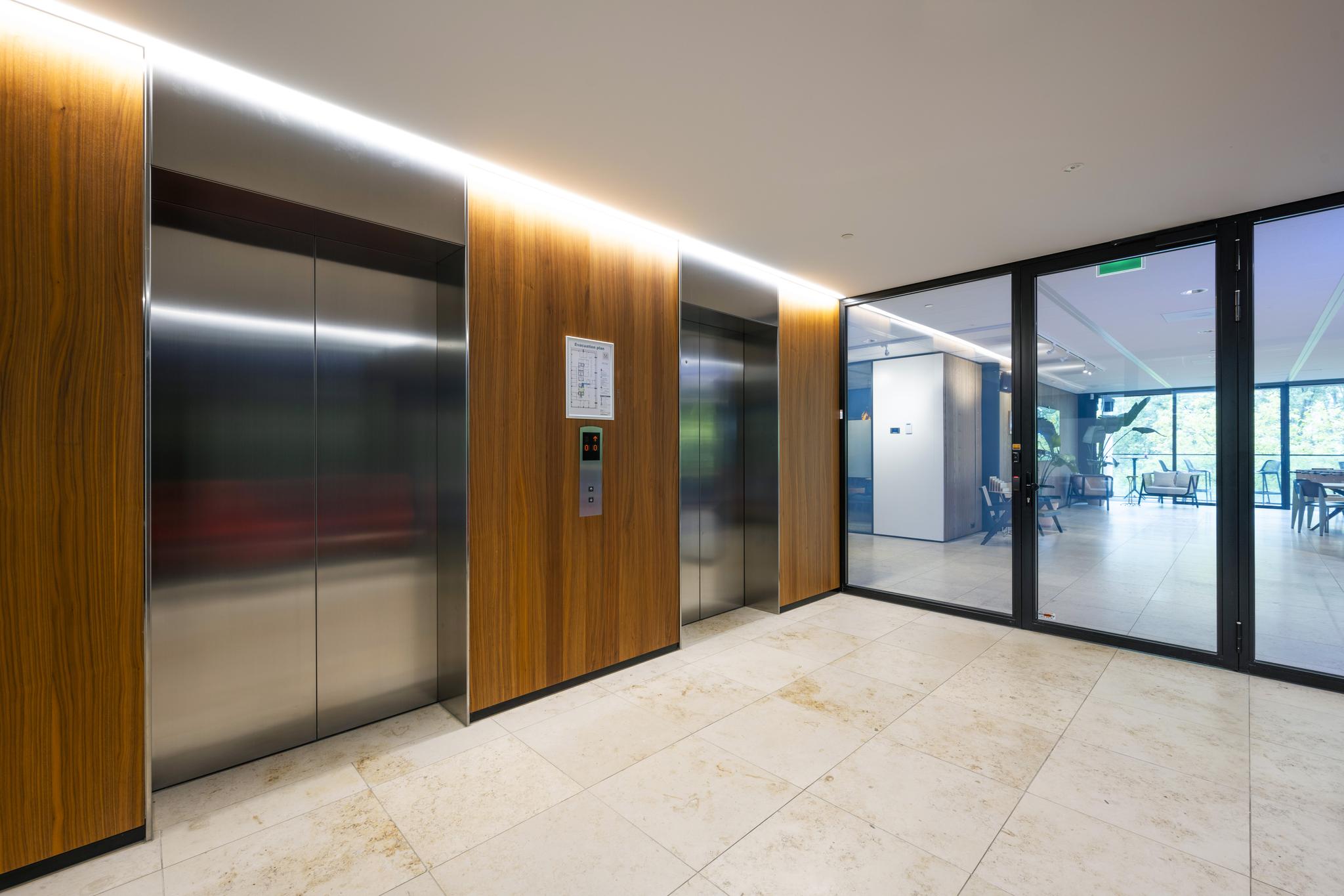 Moderne liftlobby met houten afwerking en glazen deur aan de Gustav Mahlerlaan.