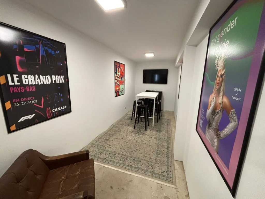 Een moderne zithoek aan de Van Ostadestraat met posters aan de muur, een hoge tafel met krukken en een televisie aan de wand.