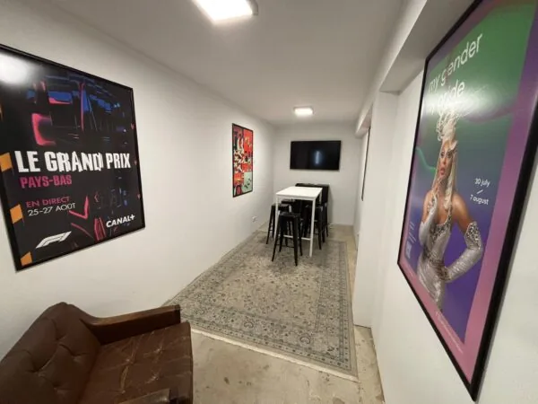 Een moderne zithoek aan de Van Ostadestraat met posters aan de muur, een hoge tafel met krukken en een televisie aan de wand.