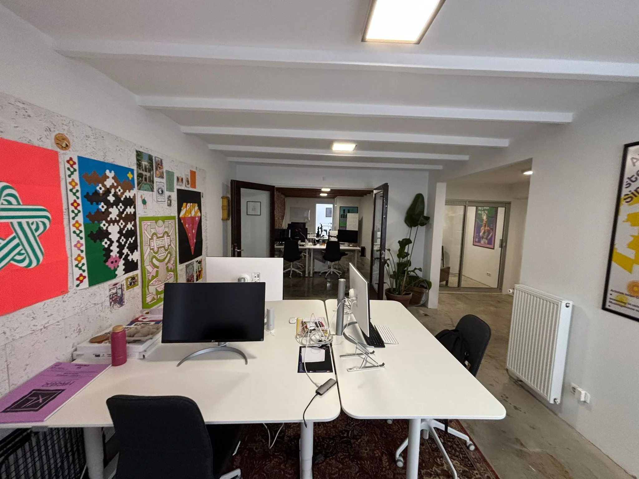 Modern kantoorinterieur aan de Van Ostadestraat met witte bureaus, kleurrijke muurkunst en computeropstellingen.