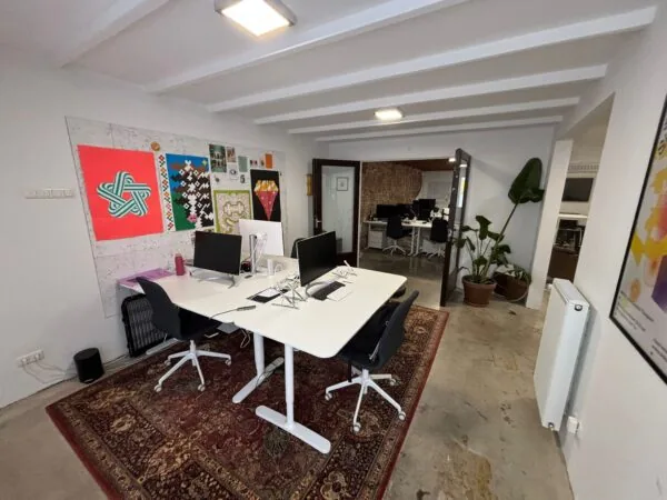 Modern kantoor met witte bureaus, kleurrijke posters aan de muur en een oosters tapijt op de vloer aan de Van Ostadestraat.