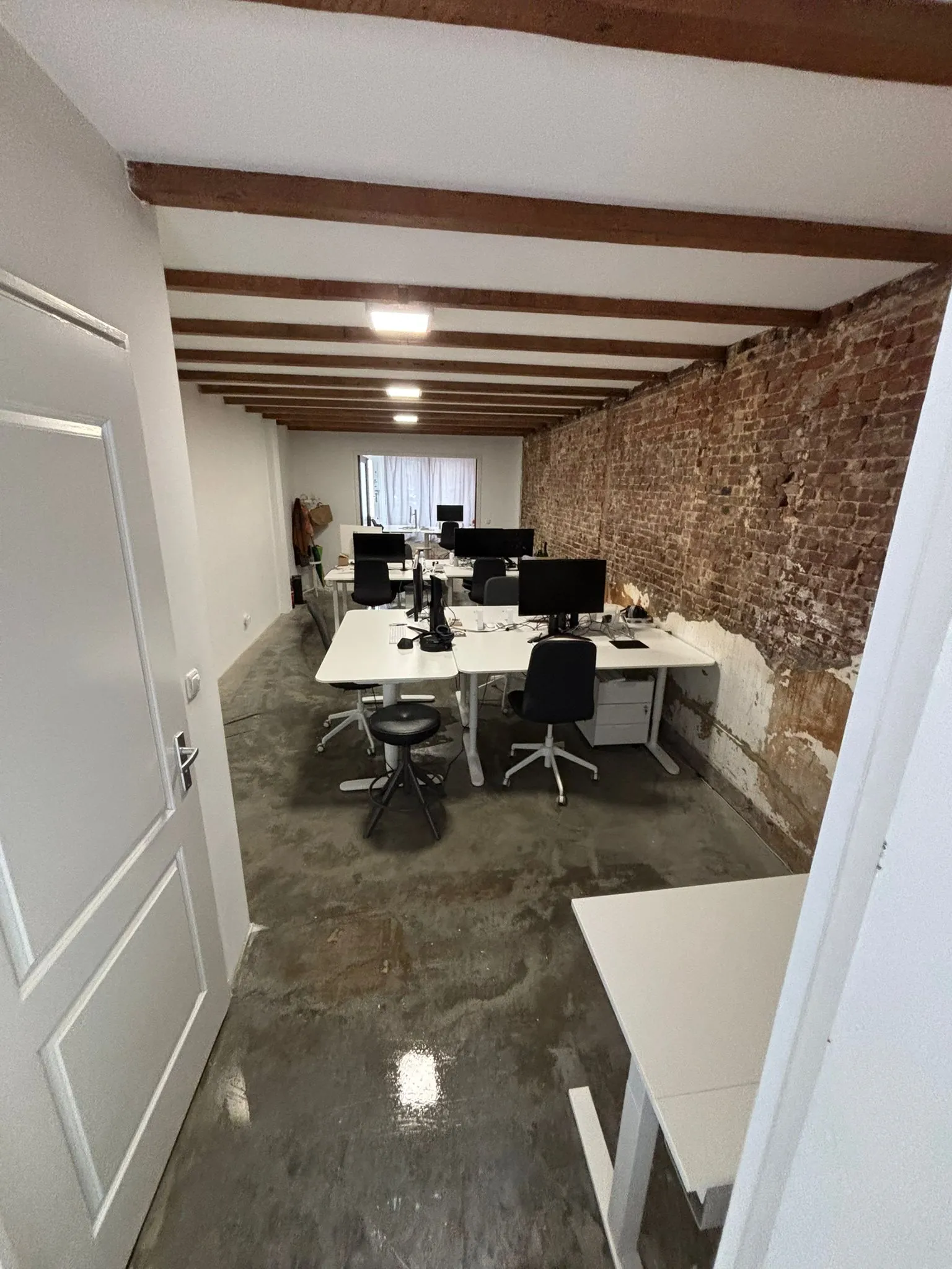 Moderne kantoorruimte aan de Van Ostadestraat met meerdere bureaus, computers en een bakstenen muur.