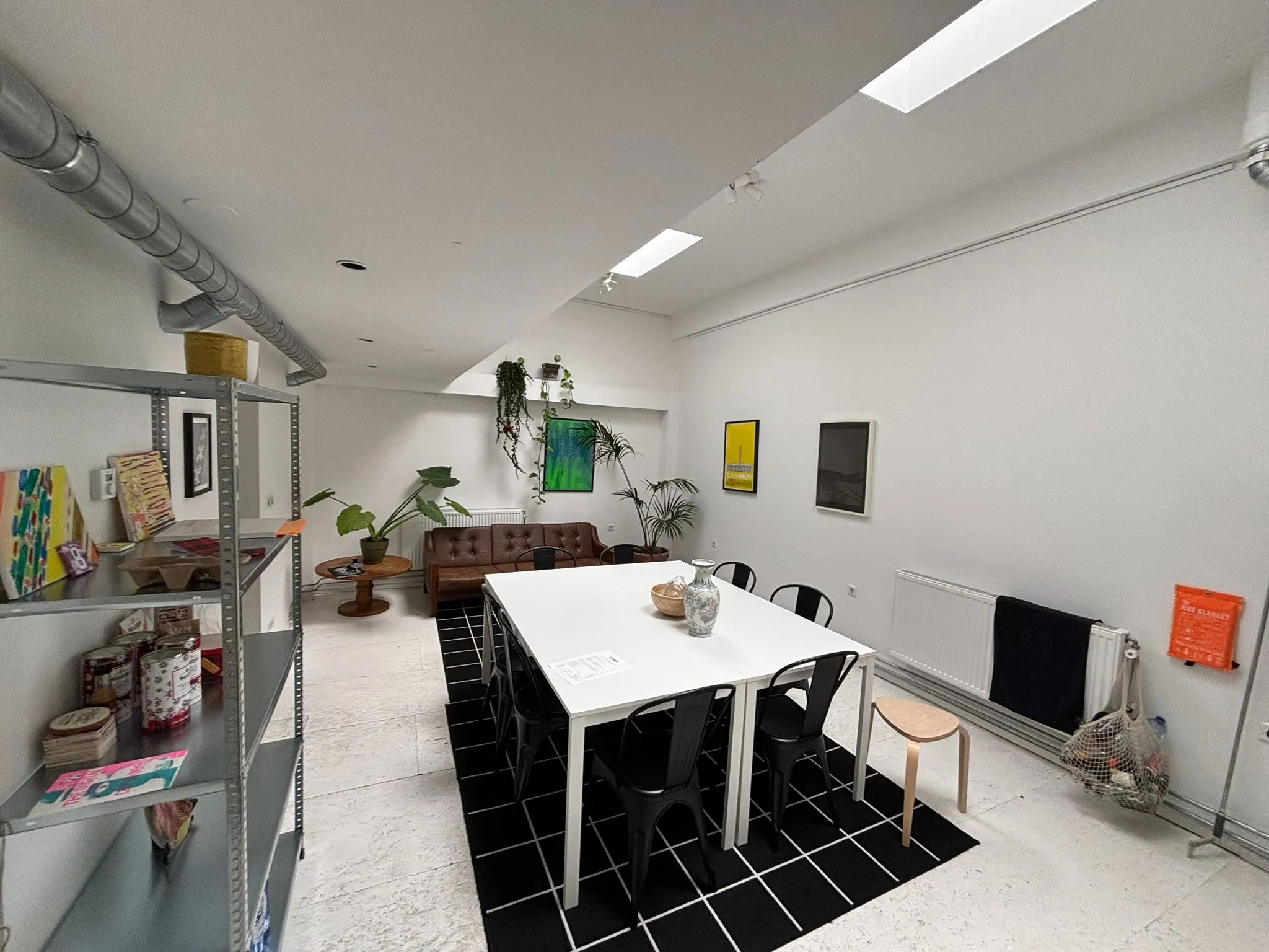 Moderne, lichte vergaderruimte aan de Van Ostadestraat met een lange tafel, zwarte stoelen, planten en kunst aan de muur.