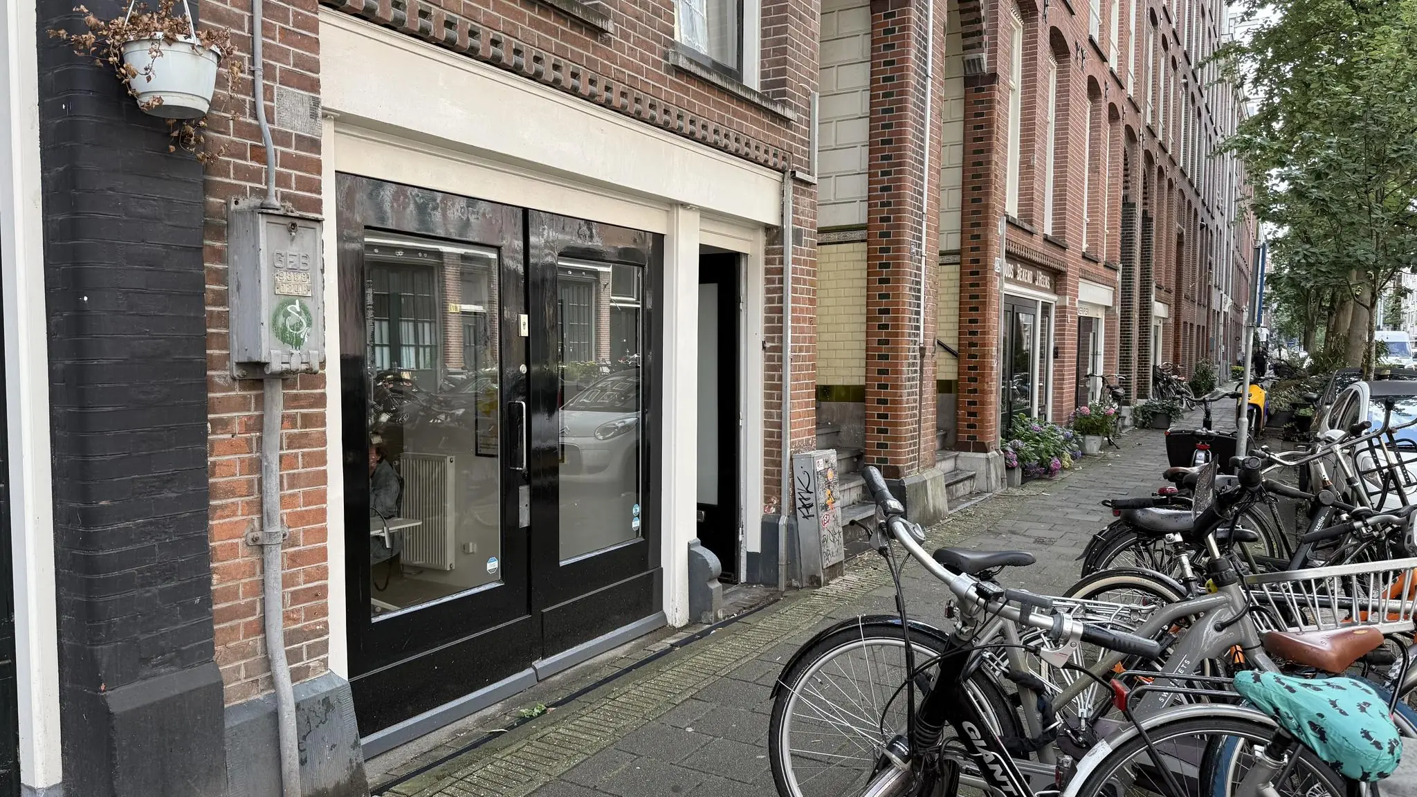 Straatbeeld van de Van Ostadestraat met fietsen, bakstenen gevels en een zwarte voordeur links.