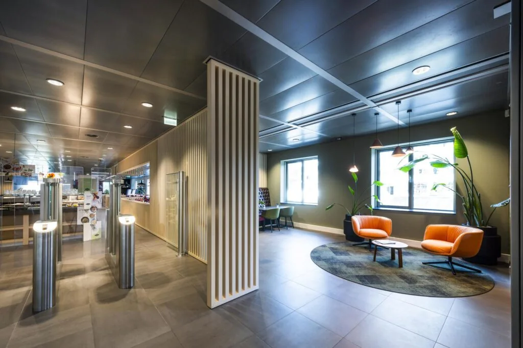 Moderne wachtruimte en entreehal op het Koningin Wilhelminaplein met zitgedeelte, toegangspoortjes en een bedrijfsrestaurant.