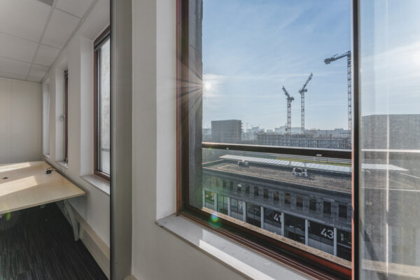 Uitzicht vanuit een kantoorraam op bouwkranen en een gebouw met nummers 41 en 43.