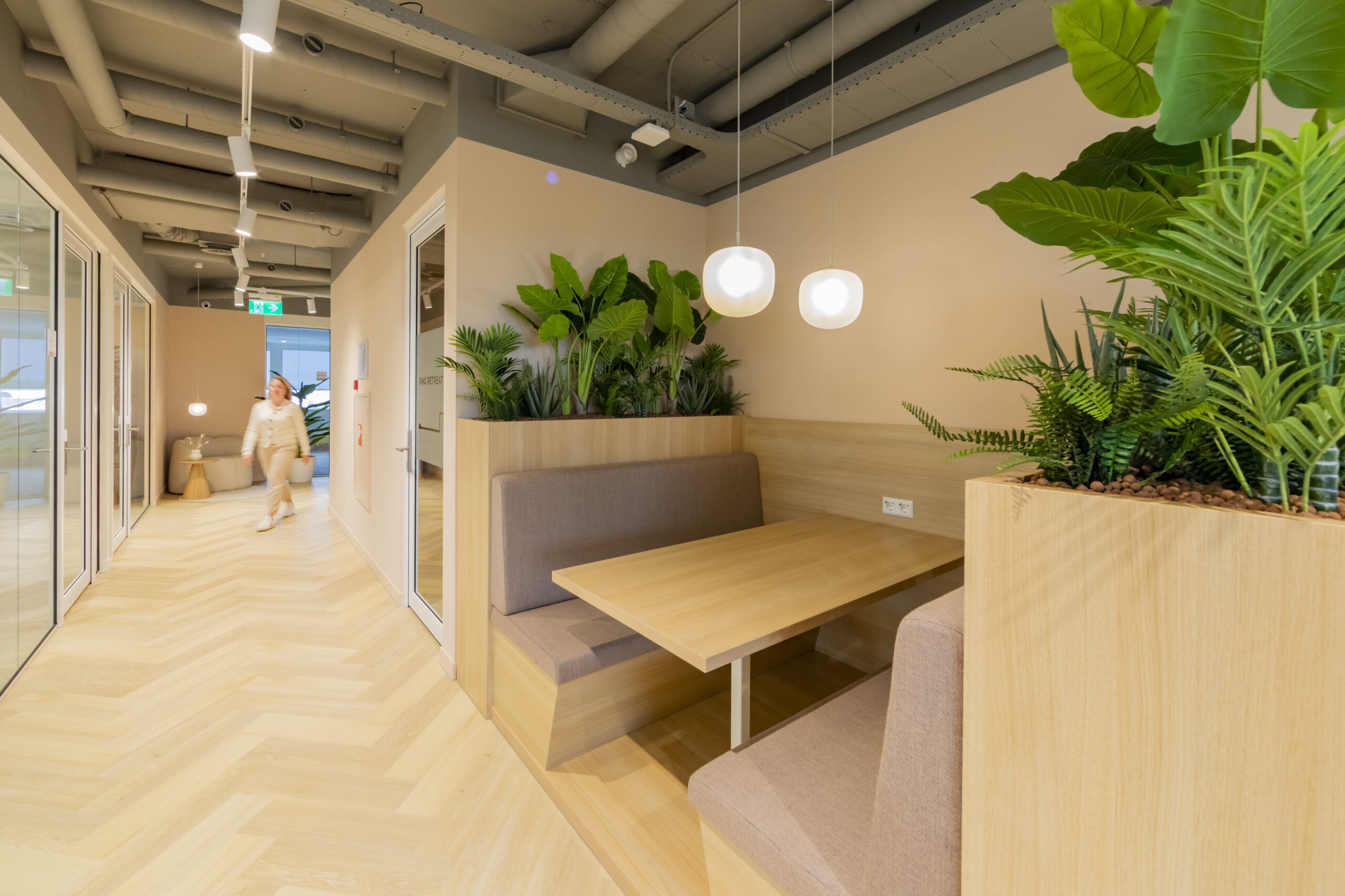 Een modern kantoorinterieur met een houten zithoek en veel groene planten.