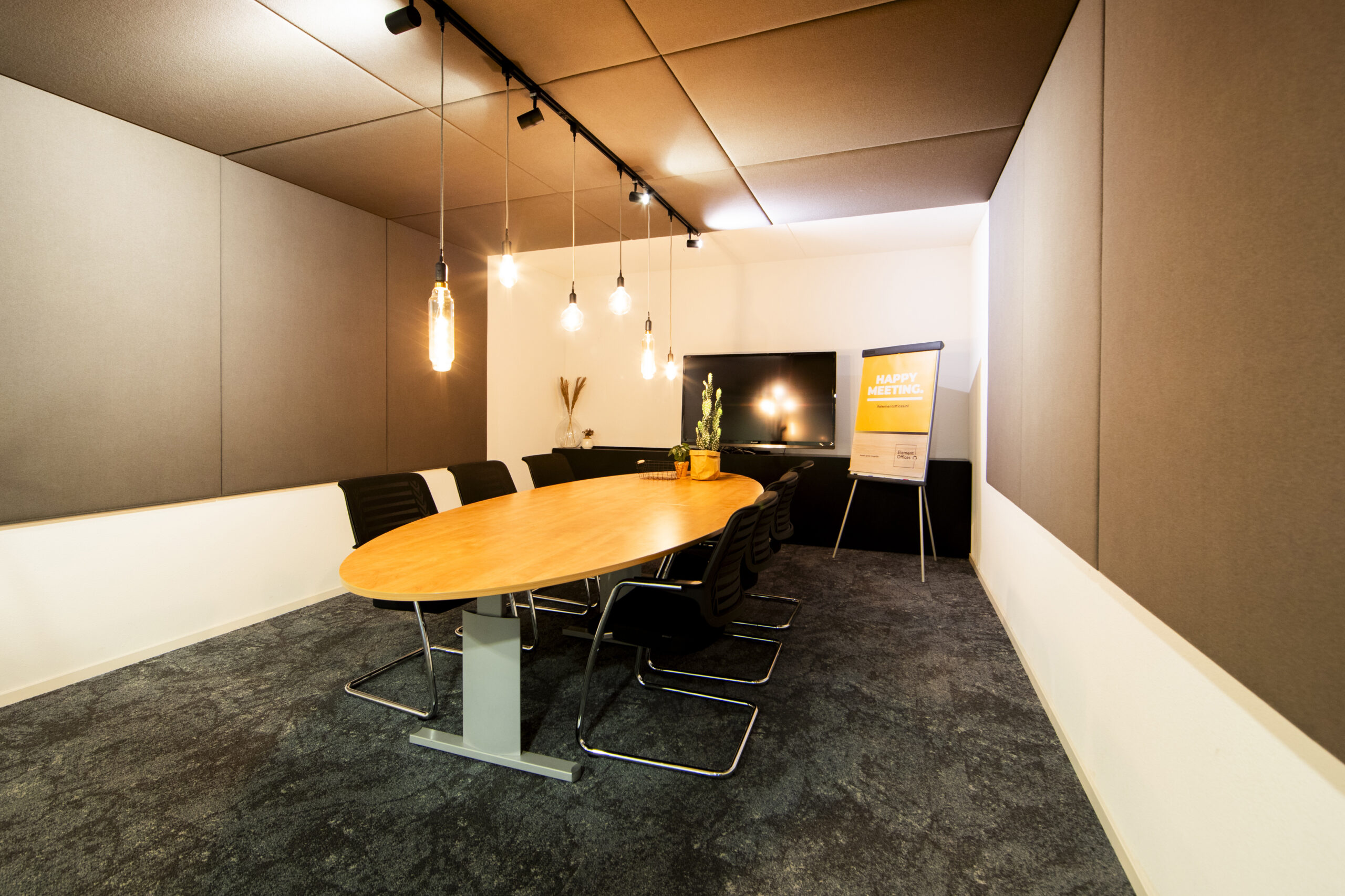 Een moderne vergaderruimte in Vleuterweide met een lange ovale tafel en comfortabele stoelen, sfeervol verlicht door hanglampen.