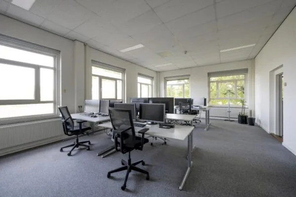 Modern en licht kantoorinterieur aan de Van der Madeweg met meerdere bureaus, computerschermen en ergonomische bureaustoelen.