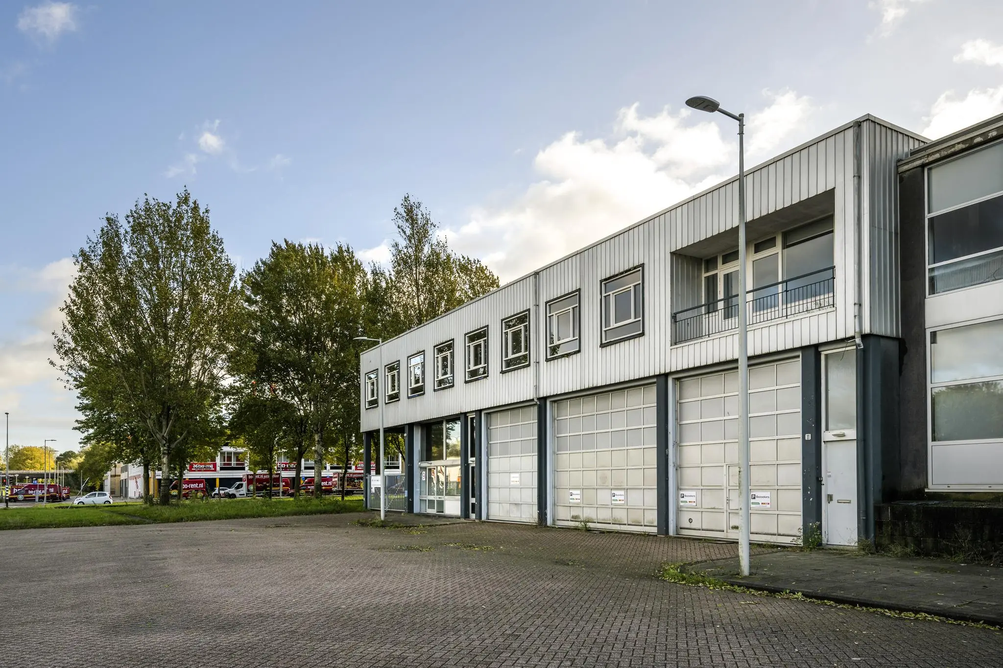 Bedrijfspand aan de Van der Madeweg met meerdere garagepoorten en een lege parkeerplaats op de voorgrond.