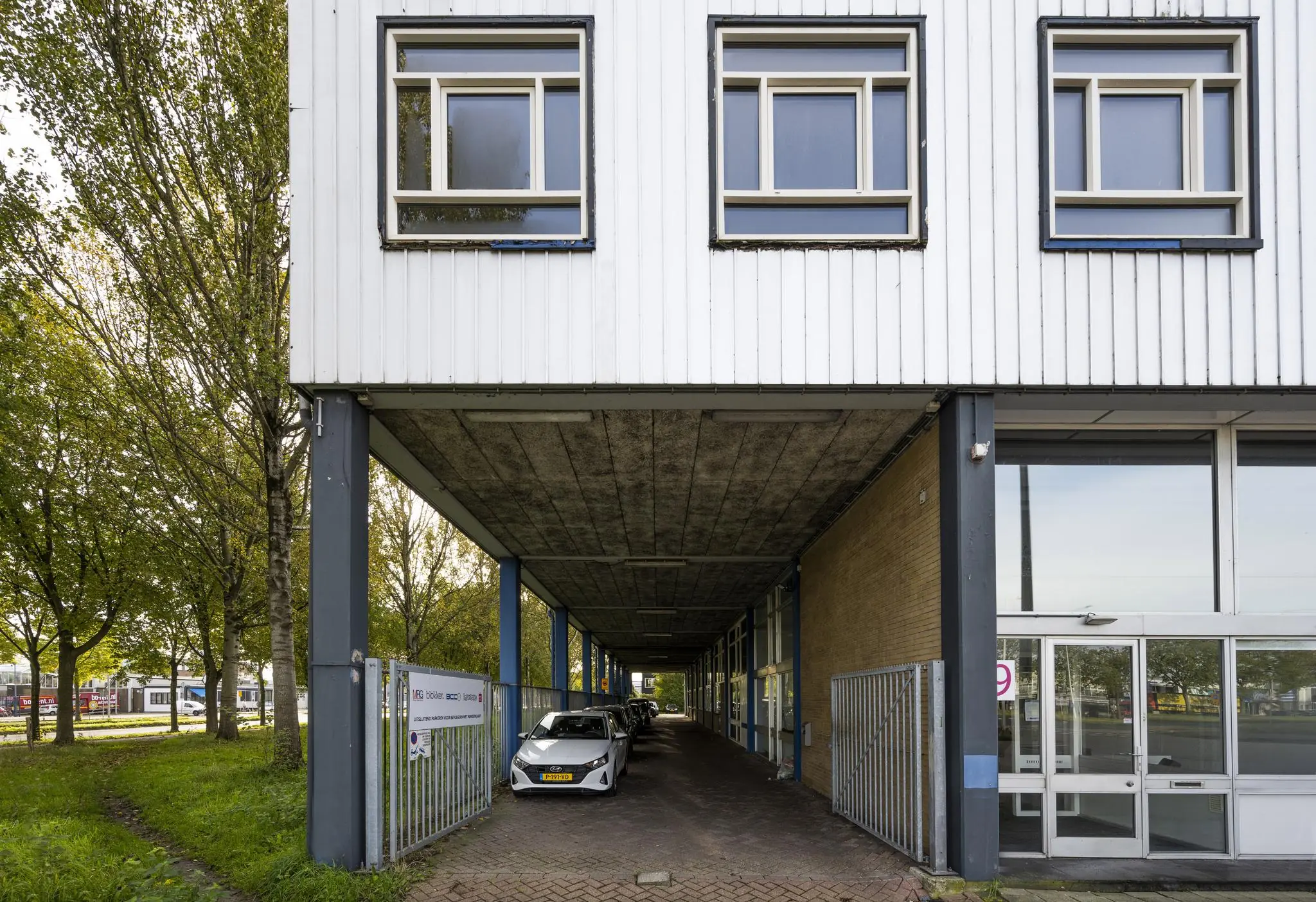 Ingang van een kantoorgebouw aan de Van der Madeweg met gedeeltelijk overdekte parkeerruimte onder het gebouw.