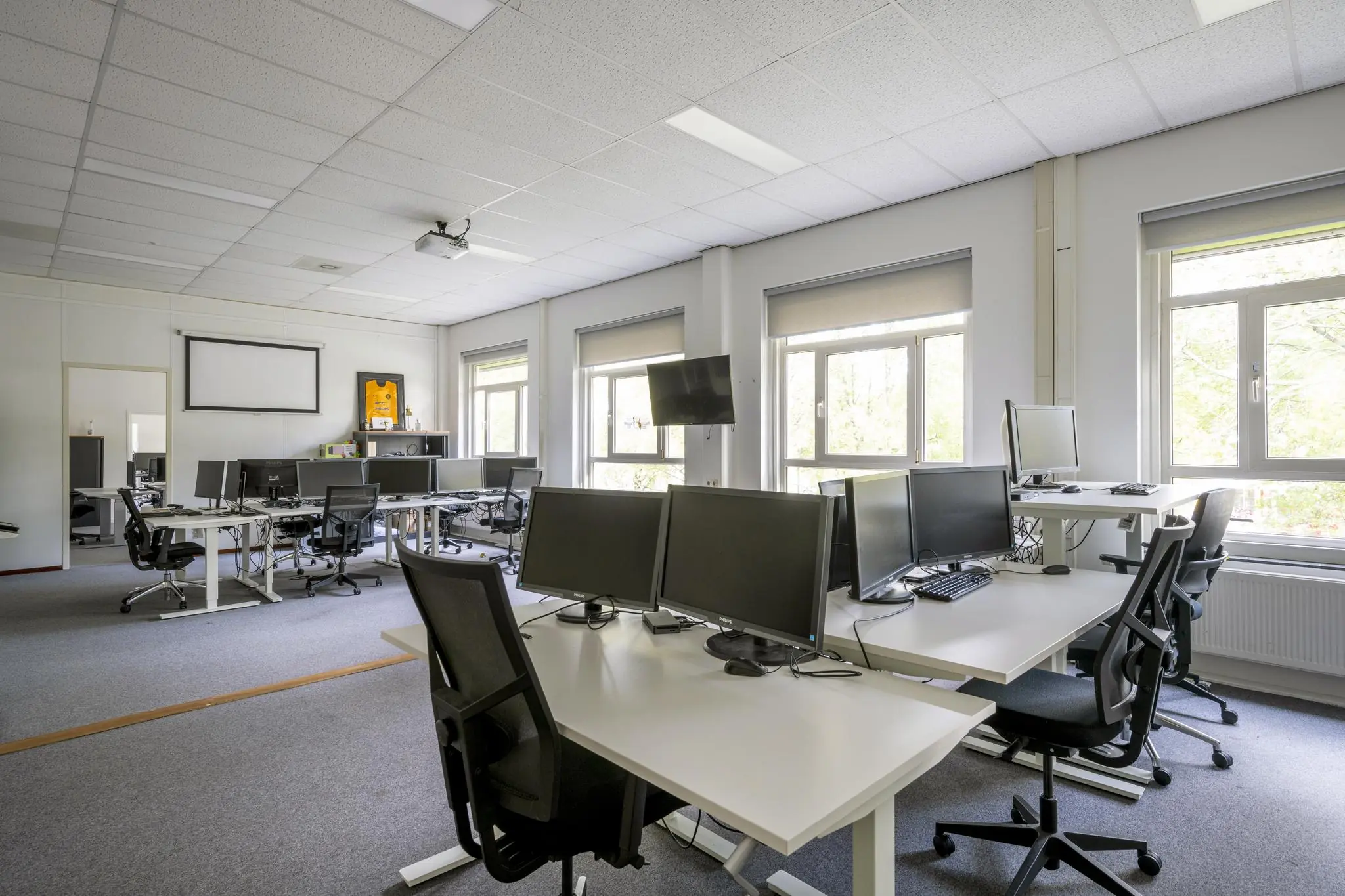 Modern en licht kantoor aan de Van der Madeweg met meerdere bureaus, computerschermen en ergonomische bureaustoelen.