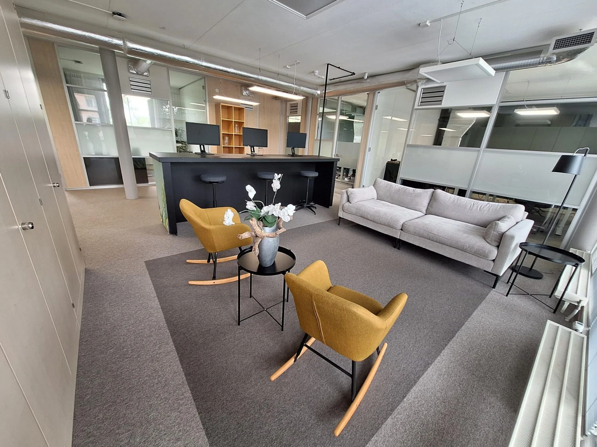 Modern ingericht kantoor aan de Jan Leentvaarlaan met loungehoek, gele schommelstoelen en werkplekken met computers.