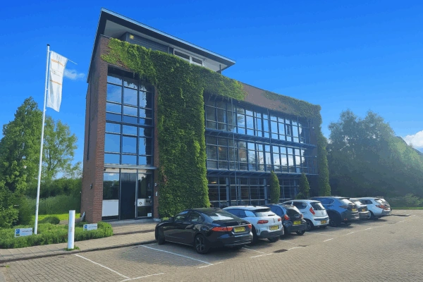 Modern kantoorgebouw aan de Jan Leentvaarlaan met glazen gevel en begroeide buitenmuur, omringd door geparkeerde auto's.