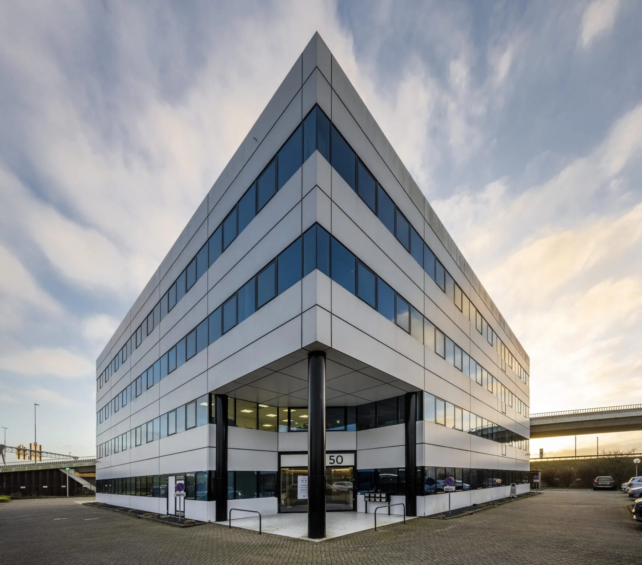 Modern kantoorpand aan de Kuiperbergweg 50 in Amsterdam, met strakke gevel en spiegelende ramen.