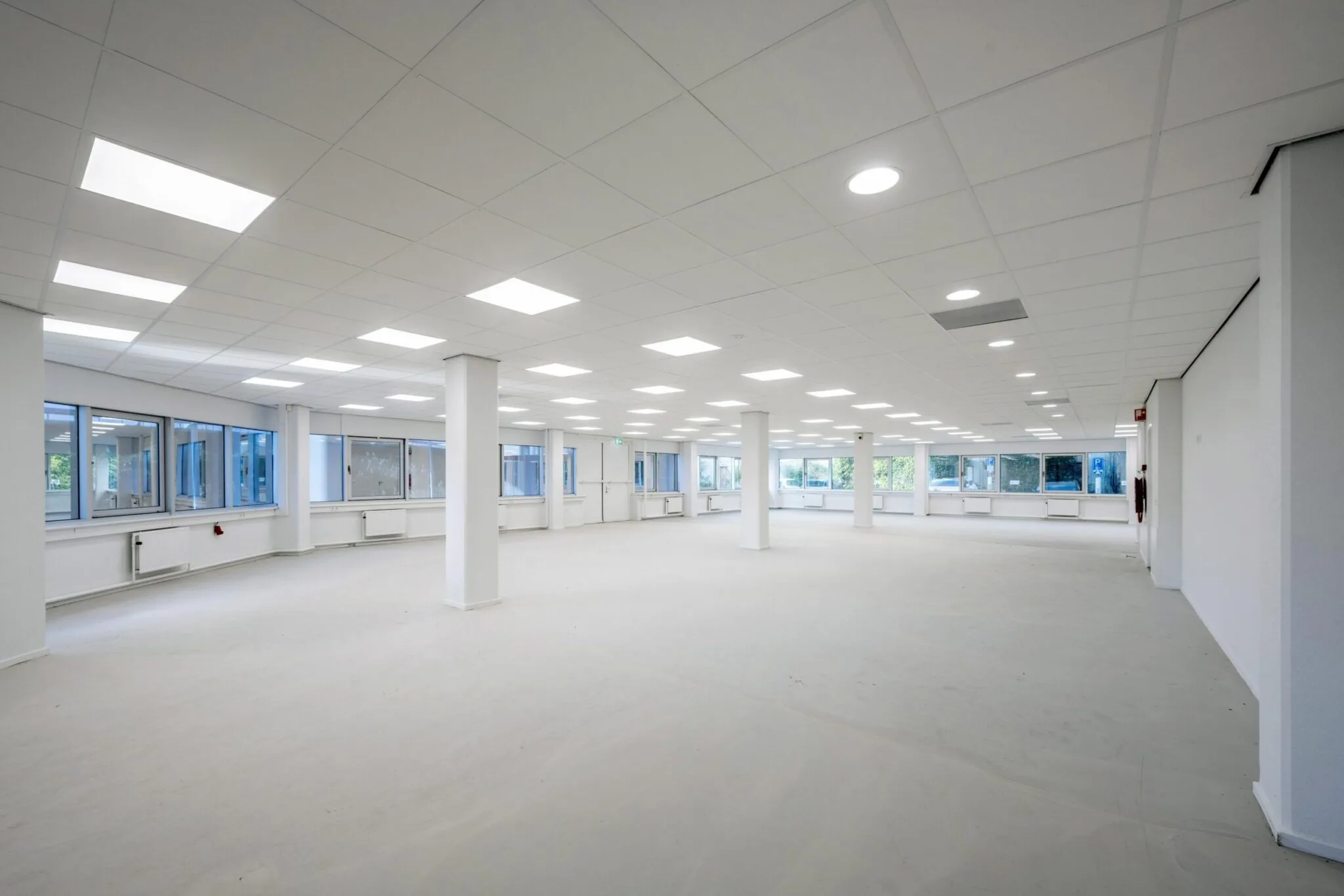 Lichte, lege kantoorruimte aan de Kuiperbergweg met grote ramen en systeemplafond.
