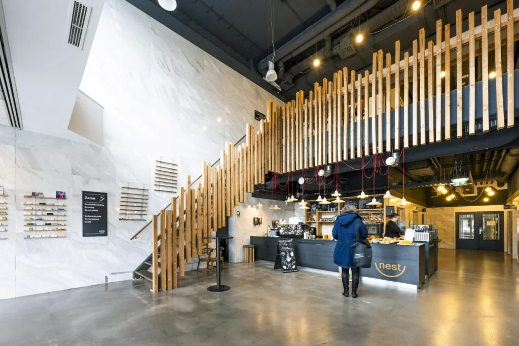 Moderne entreehal met koffiebar Nest, houten trap en inrichting in Laan van Kronenburg.
