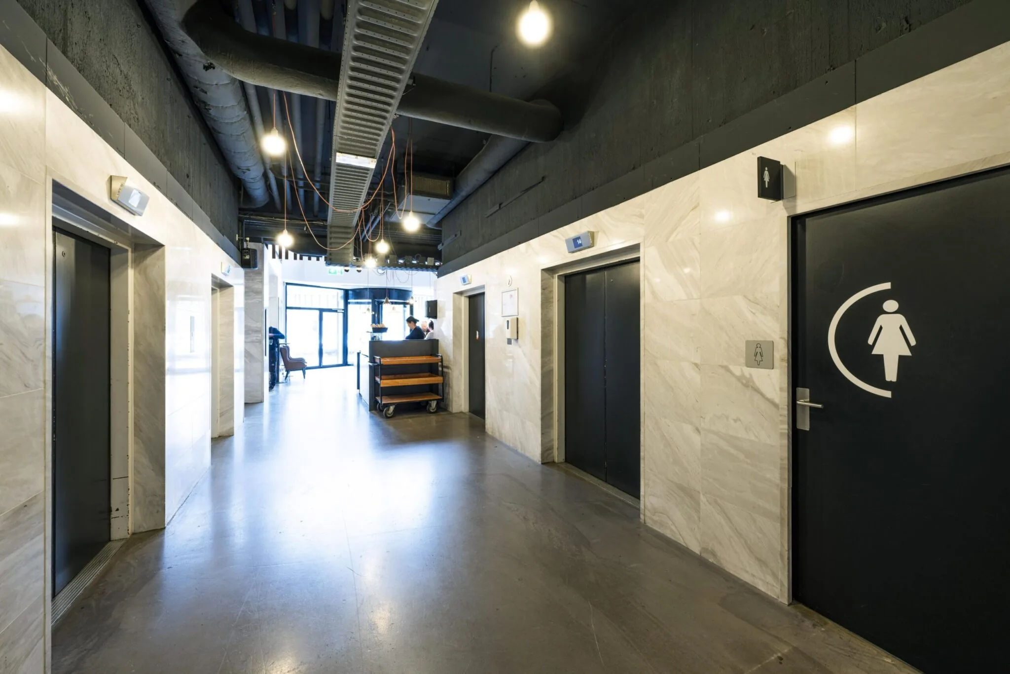 Hal met liften en een damestoilet in een modern kantoorgebouw aan de Laan van Kronenburg.