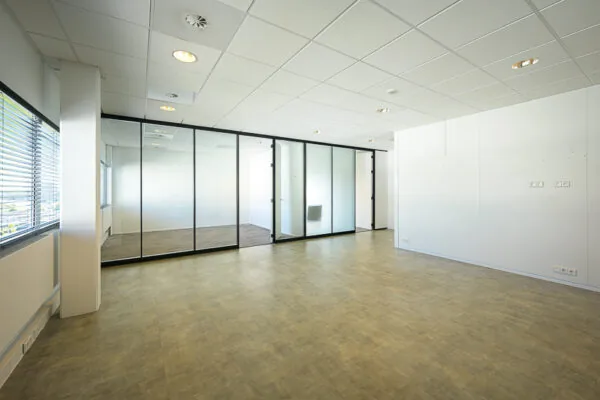 Lichte, lege kantoorruimte aan de K.P. van der Mandelelaan met glazen tussenwanden en systeemplafond.