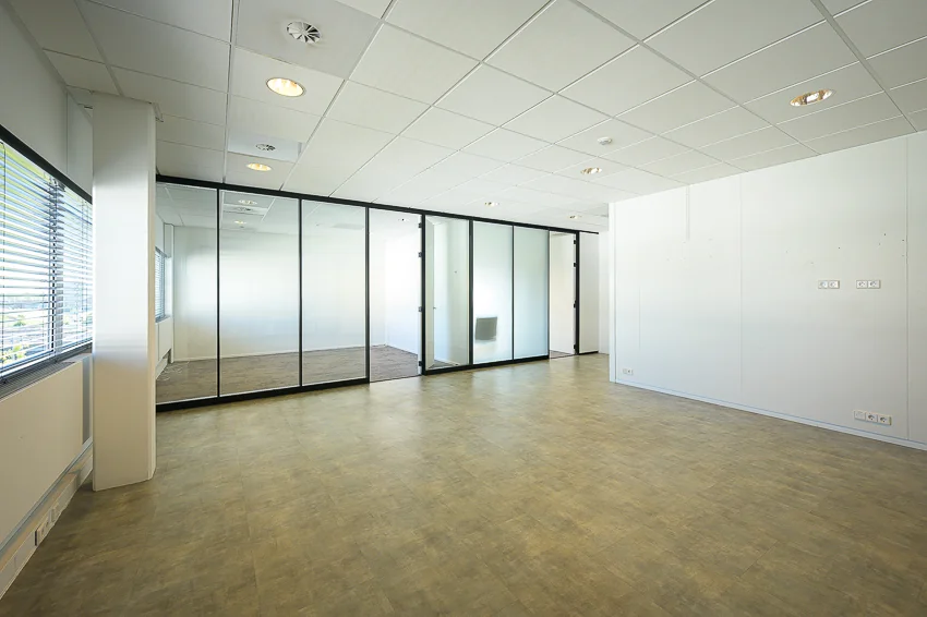 Lichte, lege kantoorruimte aan de K.P. van der Mandelelaan met glazen tussenwanden en systeemplafond.