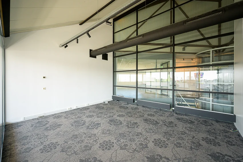 Leeg kantoor met glazen wand en uitzicht op trappenhuis aan de K.P. van der Mandelelaan.