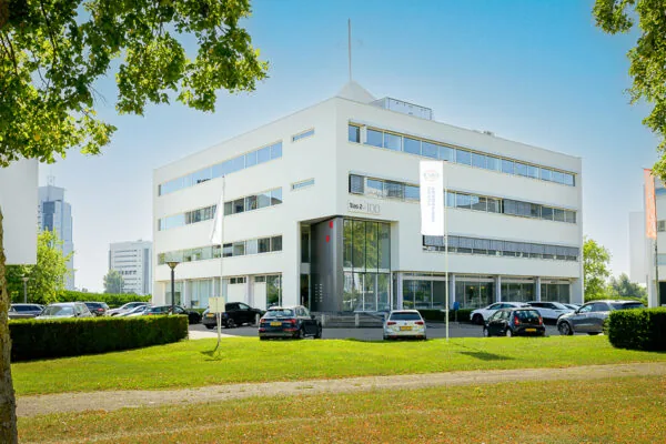 Modern kantoorgebouw aan de K.P. van der Mandelelaan met parkeerplaatsen en omliggend groen.
