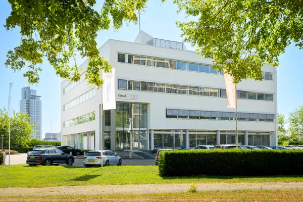 Modern kantoorgebouw aan de K.P. van der Mandelelaan in Rotterdam, omringd door geparkeerde auto's en groen.