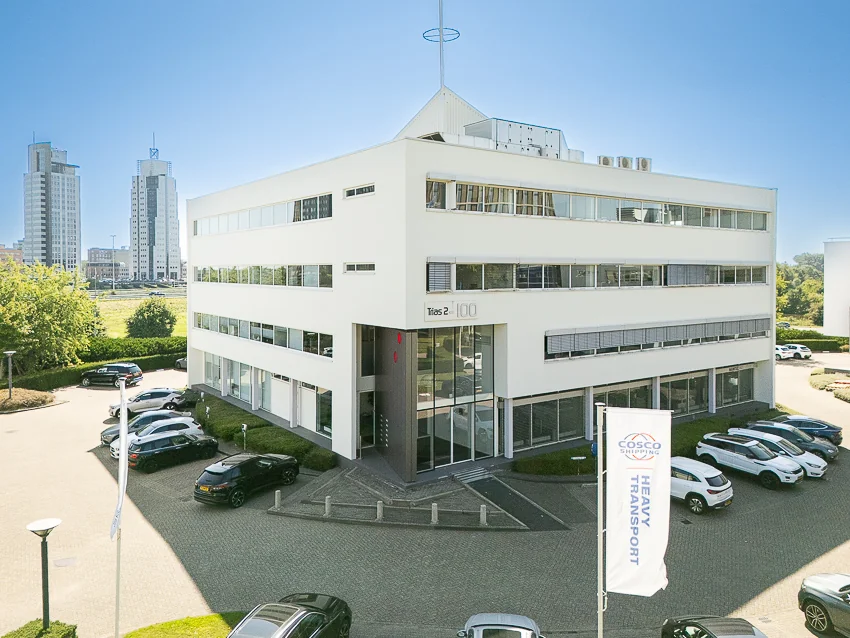 Wit kantoorgebouw aan de K.P. van der Mandelelaan met het bord "Trias 2 – 100" bij de entree en geparkeerde auto's op de voorgrond.