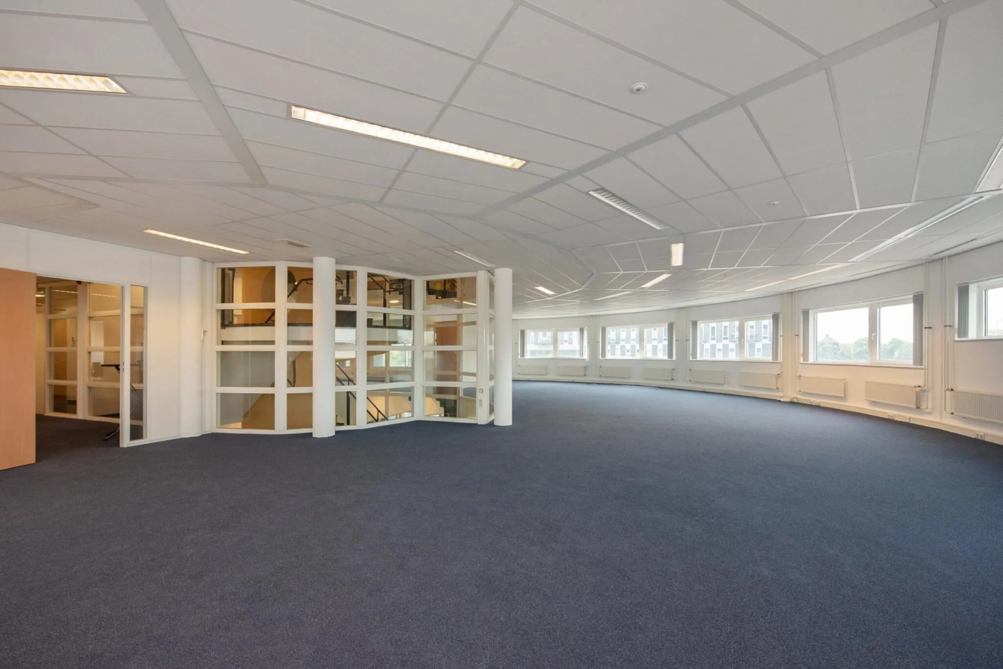 Ruime, lege kantoorruimte aan de Binckhorstlaan met grote ramen en glazen binnenwanden.