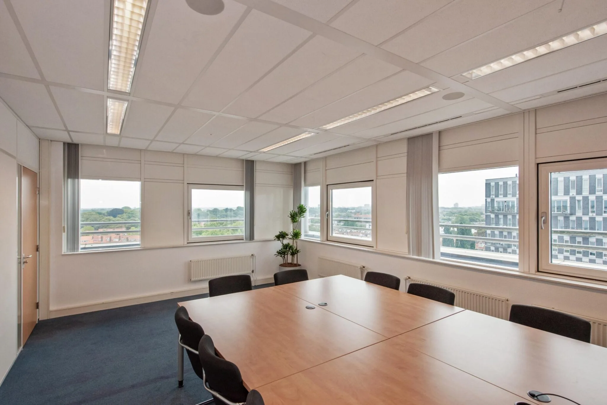 Vergaderruimte met grote ramen, vergadertafel en uitzicht op de Binckhorstlaan in Den Haag.