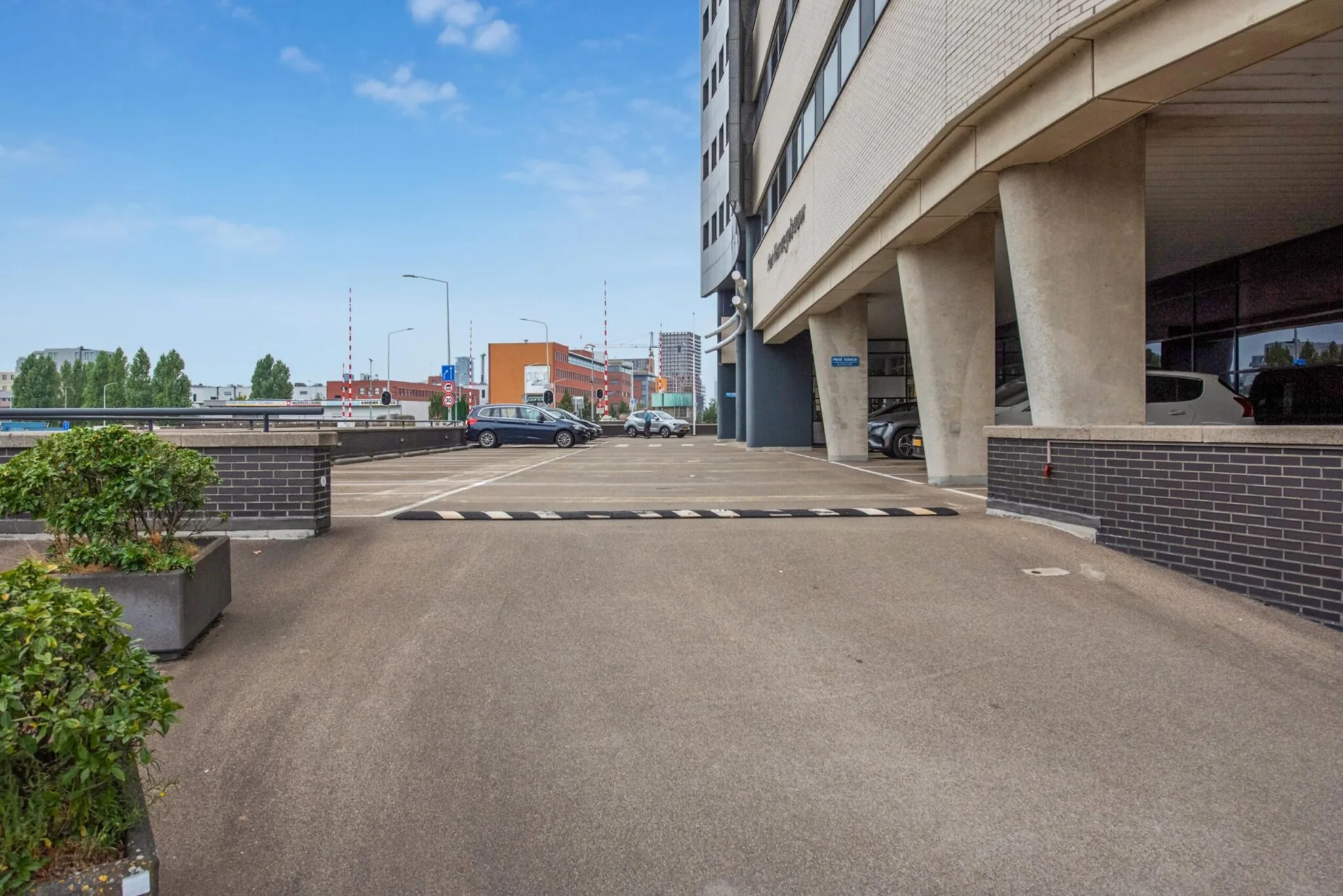 Ingang van een parkeergarage aan de Binckhorstlaan met zicht op een modern kantoorgebouw en geparkeerde auto's.