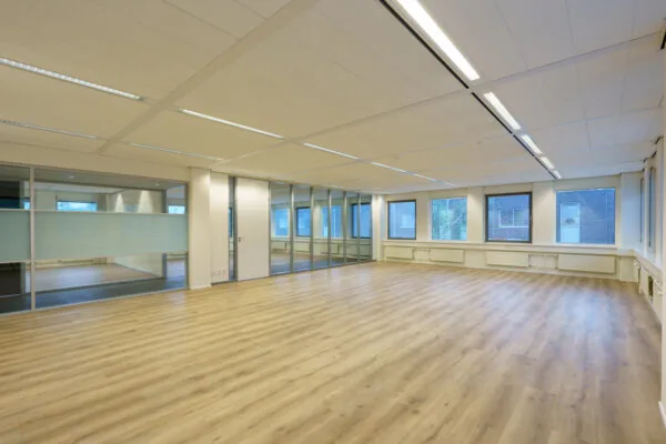 Licht en ruim kantoorpand aan de Baarnsche Dijk met houten vloer, glazen wanden en grote ramen.