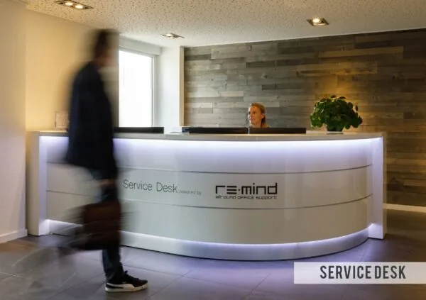 Man loopt langs moderne servicebalie van Re:mind in Baarnsche Dijk met receptioniste achter het bureau.