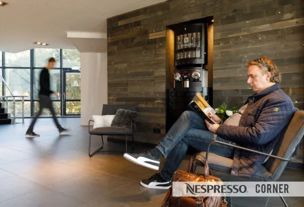 Man leest een tijdschrift in een loungeruimte bij de Nespresso Corner aan de Baarnsche Dijk.