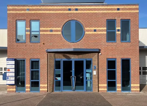 Vooraanzicht van een modern bedrijfsgebouw met rode bakstenen gevel en blauwe kozijnen, genaamd Bergveste 2.