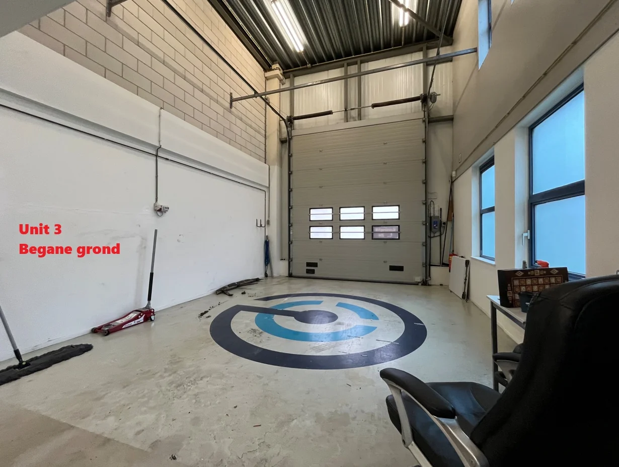 Interieur van bedrijfsunit 3 op de begane grond met hoge plafonds, een grote roldeur en glazen ramen.